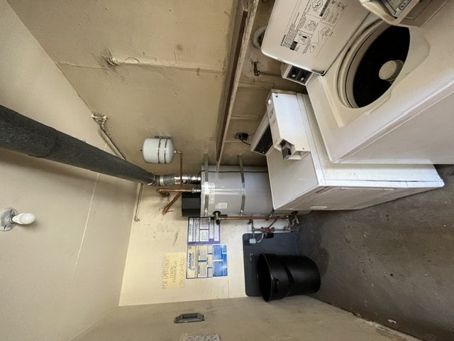 A washing machine is installed in a small room with a concrete floor.